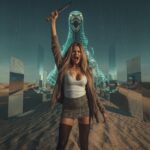 „Junge Frau steht in einer Wüste aus Spiegeln und Licht, hinter ihr ein gewaltiger Wüstenwurm aus Glas und Daten – Sinnbild für Überwachung, Simulation und die hydraulische Gesellschaft der Wahrnehmung.“